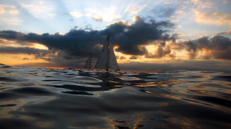 4K Sailboat in the Ocean with Sunlight and Clouds Wallpaper